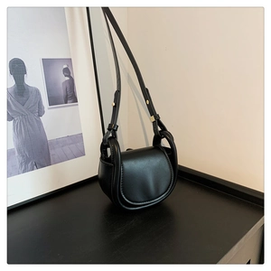 Detail of adjustable golden buckle and matte black leather strap of this saddle bag