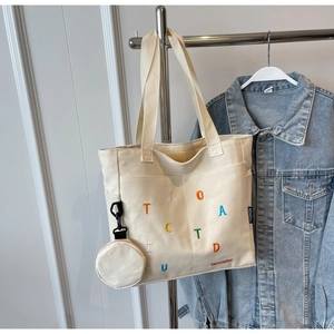 Détail du sac cabas en toile avec broderies colorées et petit porte-monnaie assorti