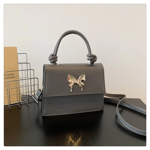 Détail du mini sac à main gris avec boucle papillon argentée et poignée à nœuds