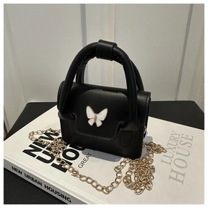Detailed macro view of black matte leather mini handbag with a white butterfly metal clasp