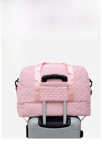 Détail du sac de voyage matelassé rose montrant la sangle de valise et la poche arrière