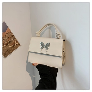 Détail du sac à main crème avec boucle papillon argentée et poignée à nœud élégante