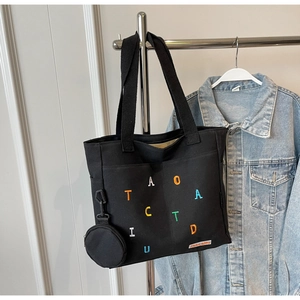 Détail du sac cabas en toile noire avec lettres brodées et pochette amovible