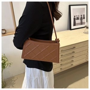 Detail showing quilted rhombus pattern and leather strap of the brown shoulder bag