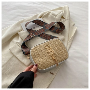 Detail of woven straw handbag featuring gold tassel, metallic buckle and ethnic strap