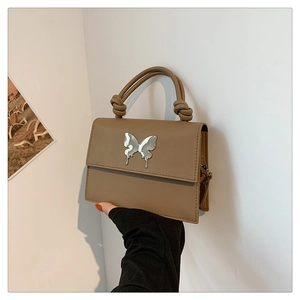 Détail du sac à main marron caramel avec fermoir papillon argenté et poignée nouée