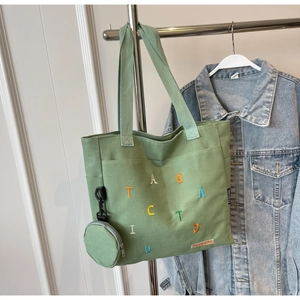 Détail du sac cabas en toile vert clair avec broderie colorée et mini porte-monnaie