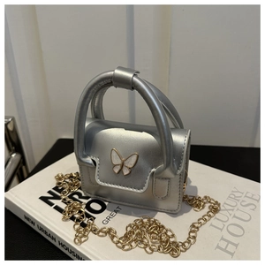 Detail of silver mini handbag with white butterfly accent and gold chain strap