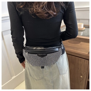 Détail du sac bandoulière noir orné de clous argentés et d'un écusson mode chic