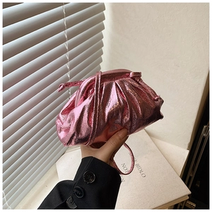 Detail of metallic pink pleated dumpling bag with pearlescent finish under natural light