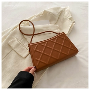 Detail shot of brown quilted crossbody bag with golden hardware on a white background