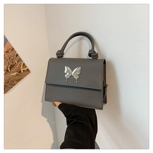 Détail du sac à main gris mat avec boucle papillon argentée et poignée à nœud torsadé