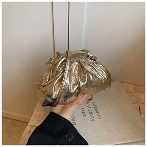 Close-up of metallic gold ruched cloud pouch bag with shiny pleated faux leather texture