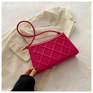 Close-up of diamond quilted pattern on magenta shoulder bag with gold metal hardware details