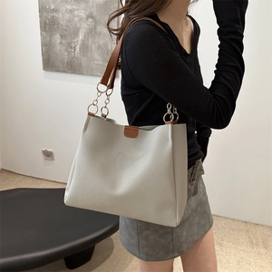 Borsa tote grigio chiaro minimalista con manici in pelle marrone e catena d'oro indossata