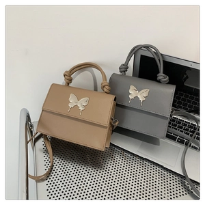 Détail de sacs à main carrés en cuir kaki et gris avec boucles papillon en métal argenté