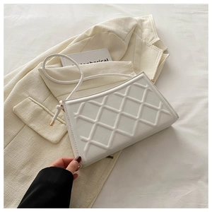 Close-up of quilted pattern details and gold hardware on a cream shoulder bag