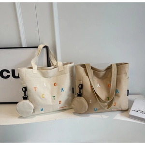 Détail du sac fourre-tout en toile avec broderie de lettres et mini pochette assortie