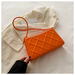 Detail of orange quilted leather shoulder bag on light blazer with fine gold hardware