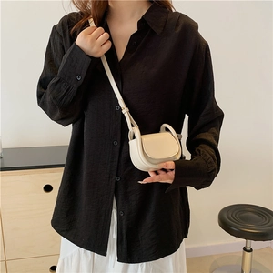 Minimalist cream white mini crossbody flap bag in smooth faux leather on model