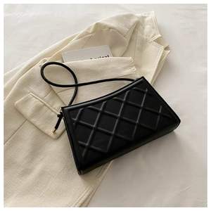 Close-up of black quilted shoulder bag texture on a stylish beige blazer background