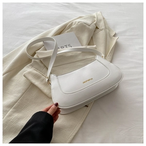 Close-up of a minimalist white faux leather shoulder bag on a beige blazer background
