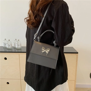 Sac à bandoulière carré gris minimaliste avec breloque papillon argentée et poignée nouée