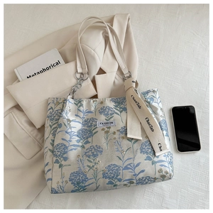 Détail du sac cabas en toile fleurie avec anse en chaîne et ruban imprimé accessoire