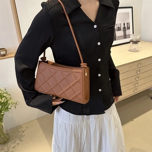 Brown quilted rectangle shoulder bag with knot strap detail in a cozy minimalist setting