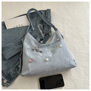 Detail of light blue nylon tote bag with pearl accents and rhinestone butterfly decor