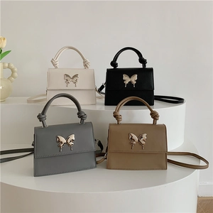 Sacs à main tendance pour femmes avec papillon en blanc, noir, gris et kaki sur présentoir