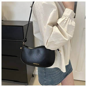 Minimalist black PU leather crescent shoulder bag with gold lettering shown on model