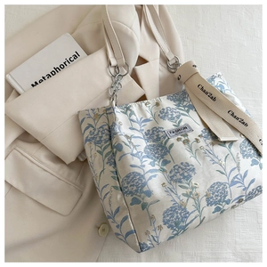 Détail du sac cabas floral avec bandoulière chaîne, étiquette mode et breloque large