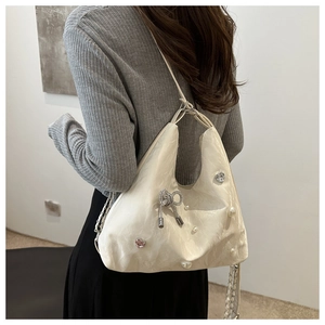 Detail of cream pleated tote bag with rhinestone butterfly and pearl embellishments