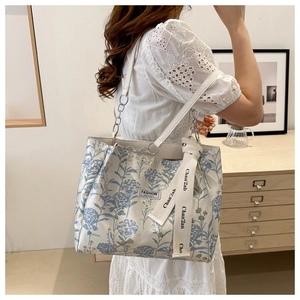 Détail du sac cabas floral avec bandoulière en chaîne et foulard en soie décoratif