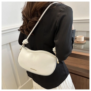 Detailed view of a white bow shoulder bag with gold hardware on a female model