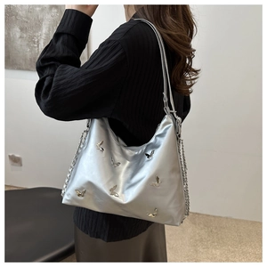 Silver metallic hobo bag with 3D butterfly details and chain strap worn by a model