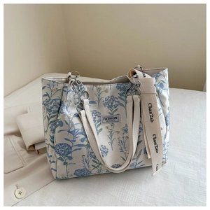 Détail du sac cabas en toile brodé de fleurs avec chaîne en métal et large bandoulière