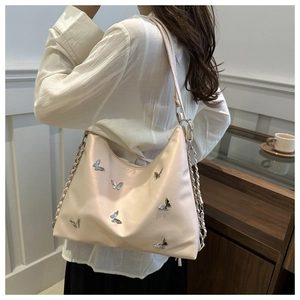 Detail of light beige hobo bag with metallic butterfly accents and chain strap