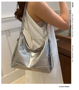 Detailed side view of silver metallic hobo bag featuring 3D butterfly metal ornaments