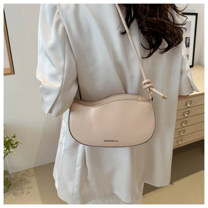 Detail of apricot crossbody bag featuring wave edge cut and knotted strap decoration