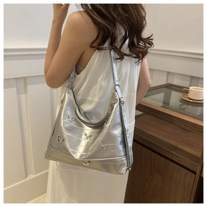 Detail of silver tote bag with 3D metal butterfly decorations and adjustable strap