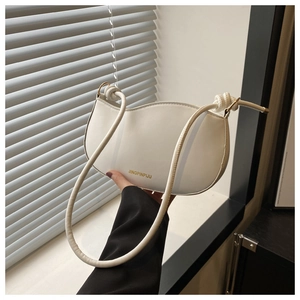 Detail of white leather shoulder bag featuring a wave-shaped top and gold brand logo