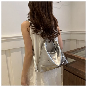 Close-up of metallic silver tote bag with pleated texture and silver butterfly charms
