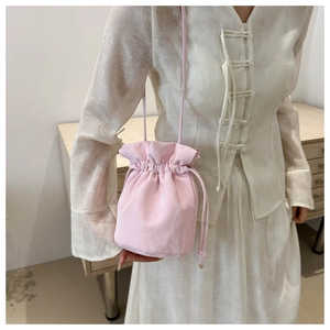Detail of pink drawstring satin bucket bag with elegant silk texture and ruffle closure