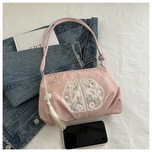 Detail of pink embroidered handbag with tassels on denim and art book background
