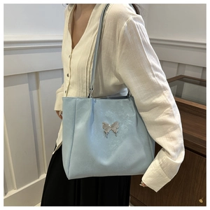 Détail d'un cabas en cuir bleu clair avec boucle papillon argentée et longue bandoulière