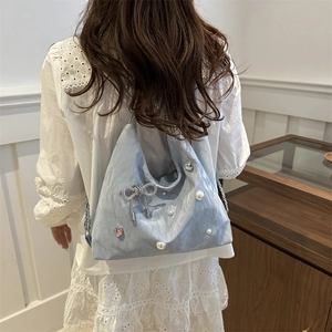 Light blue large capacity hobo bag with pearl and butterfly pendants worn by a model