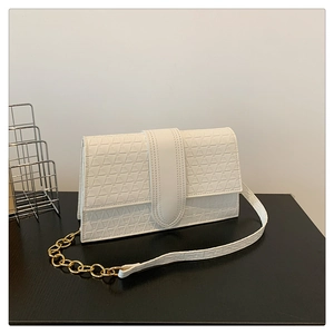 Détail du sac à main blanc avec motif géométrique gaufré et chaîne en métal doré