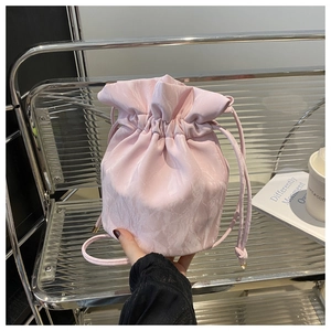 Detail of light pink drawstring bag with pleated texture and thin shoulder strap